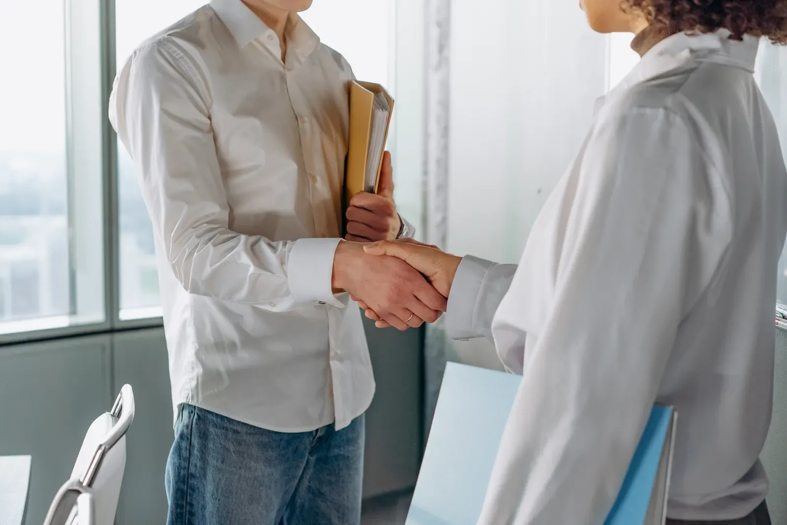 Two business professionals shaking hands in a modern office — backlinks build trust by association