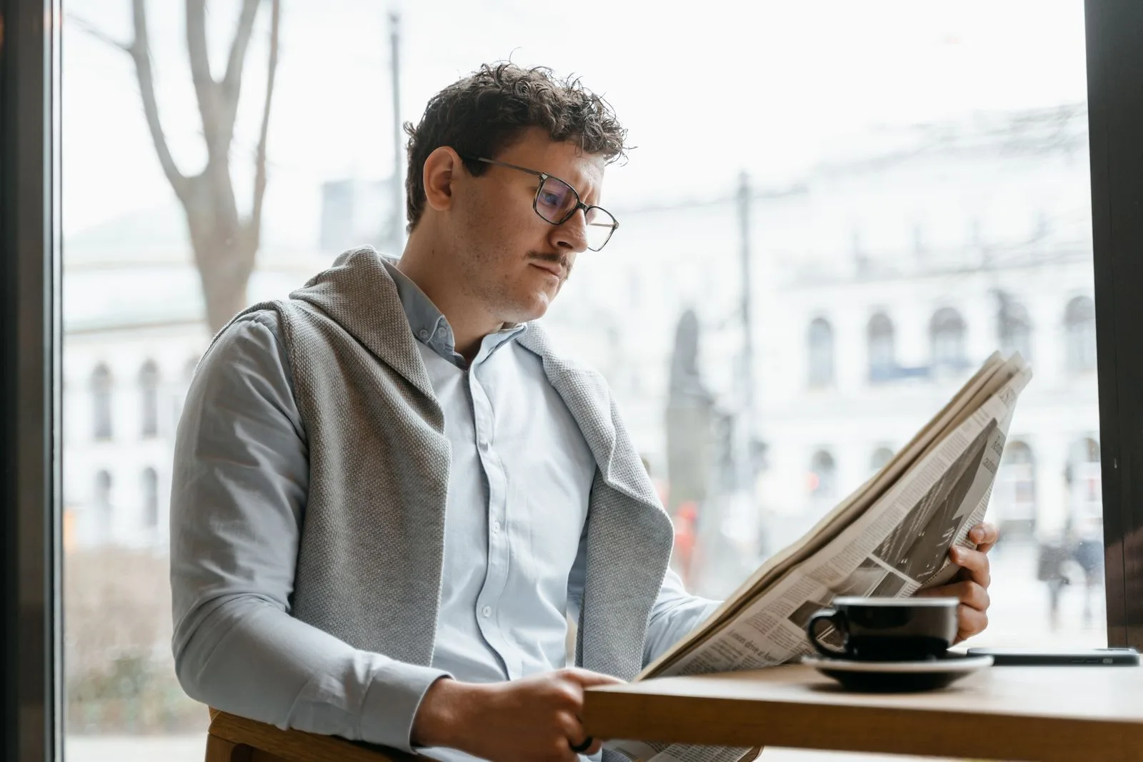 Man reading a newspaper in a café — backlink coverage puts your brand in front of media audiences