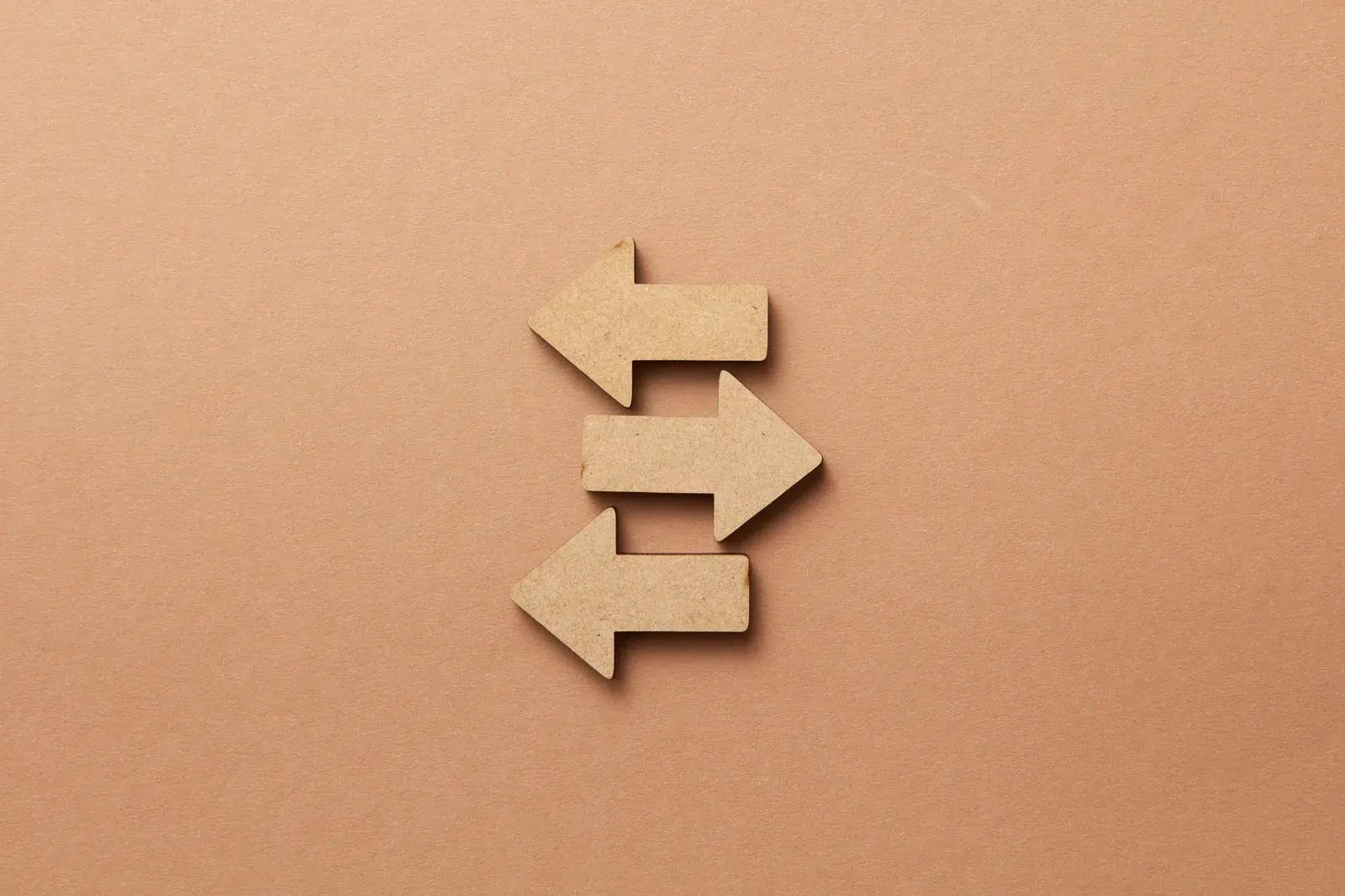 Wooden arrows pointing in opposite directions — acquisition vs building: same destination, different standards